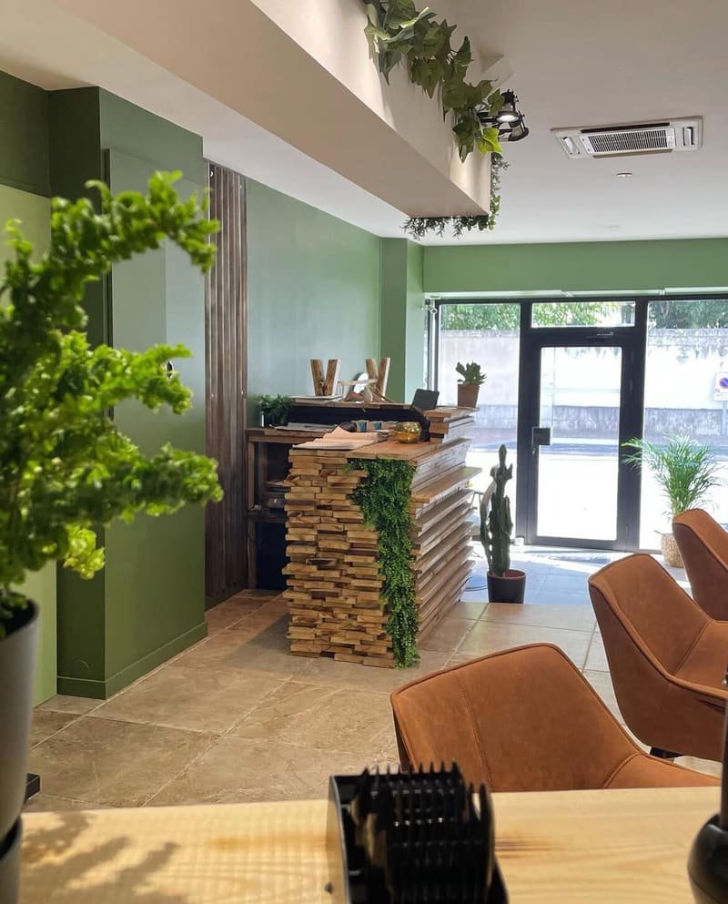 Accueil du salon La P’tite Brune : comptoir en lames de bois, plantes et entrée vitrée donnant sur la rue